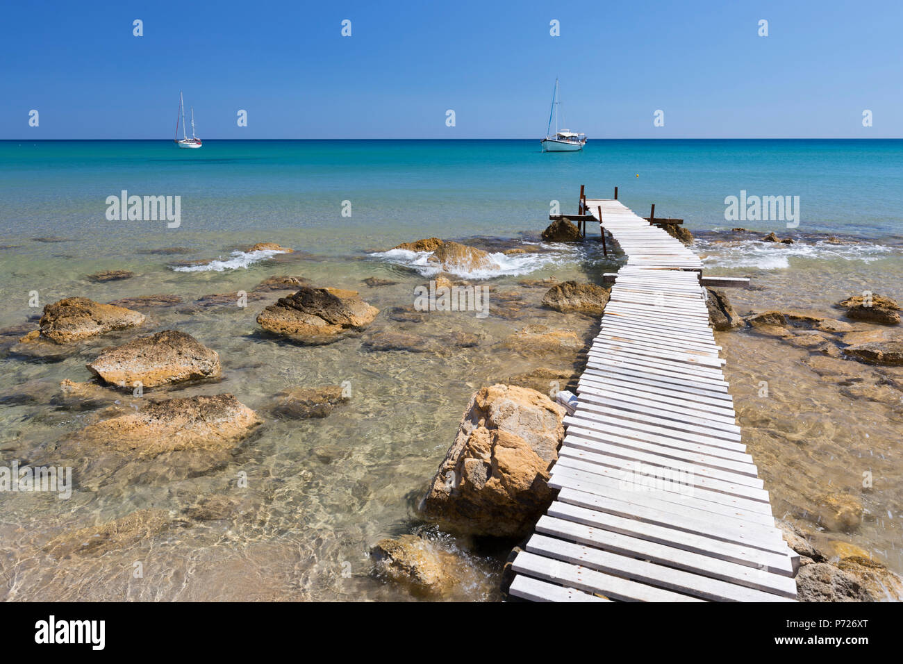 Wooden pier and clear turquoise sea with yachts at Provatas beach, Milos, Cyclades, Aegean Sea, Greek Islands, Greece, Europe Stock Photo