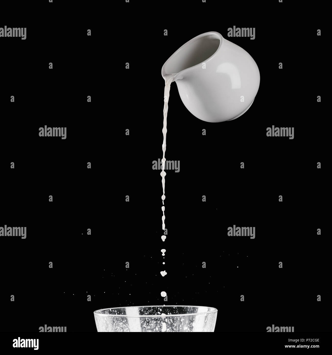 milk pouring from milk jar into bowl with flour isolated on black Stock Photo Alamy