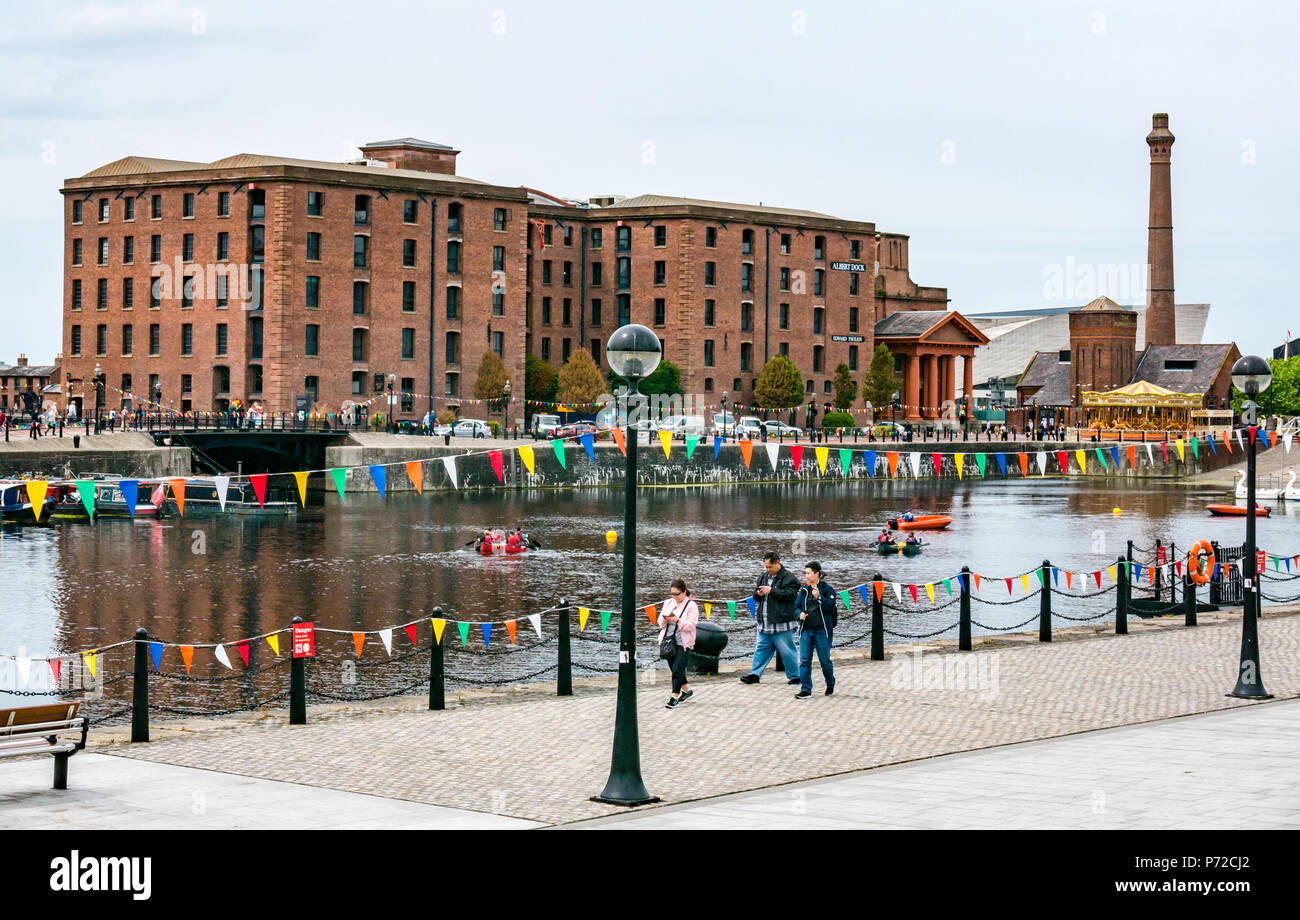 People at Salthouse Dock with Albert Dock converted warehouse and brick tower and people walking looking at phones, Liverpool, England, UK Stock Photo