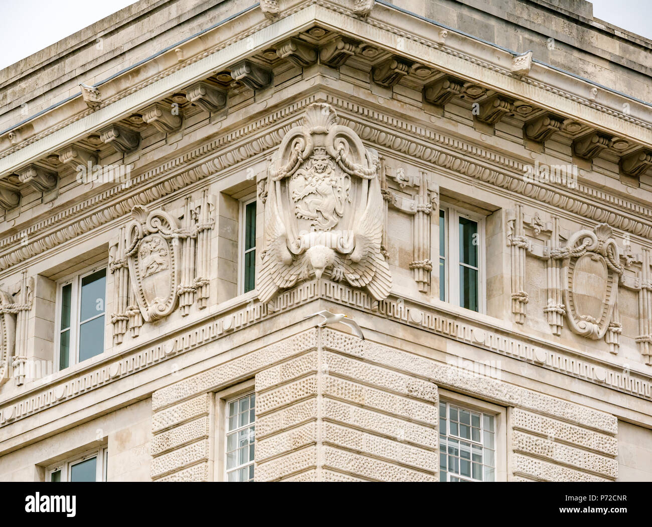 Gull flying past ornate stone carved decorative lion on corner of Cunard building, Liverpool, England, UK Stock Photo