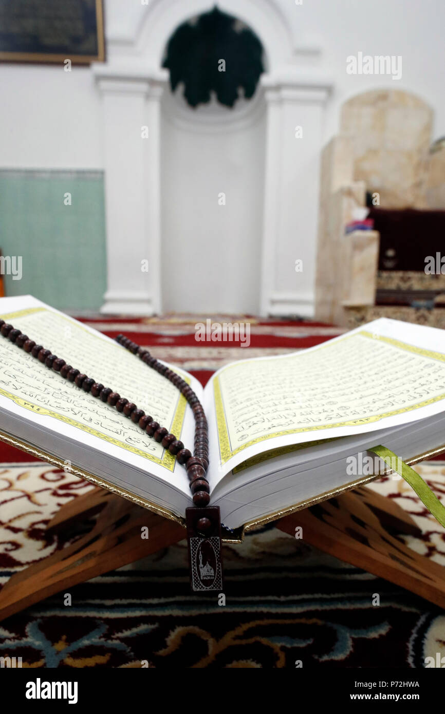 An open Holy Quran and a Muslim prayer beads on wood stand with mihrab in background, Hanoi, Vietnam, Indochina, Southeast Asia, Asia Stock Photo