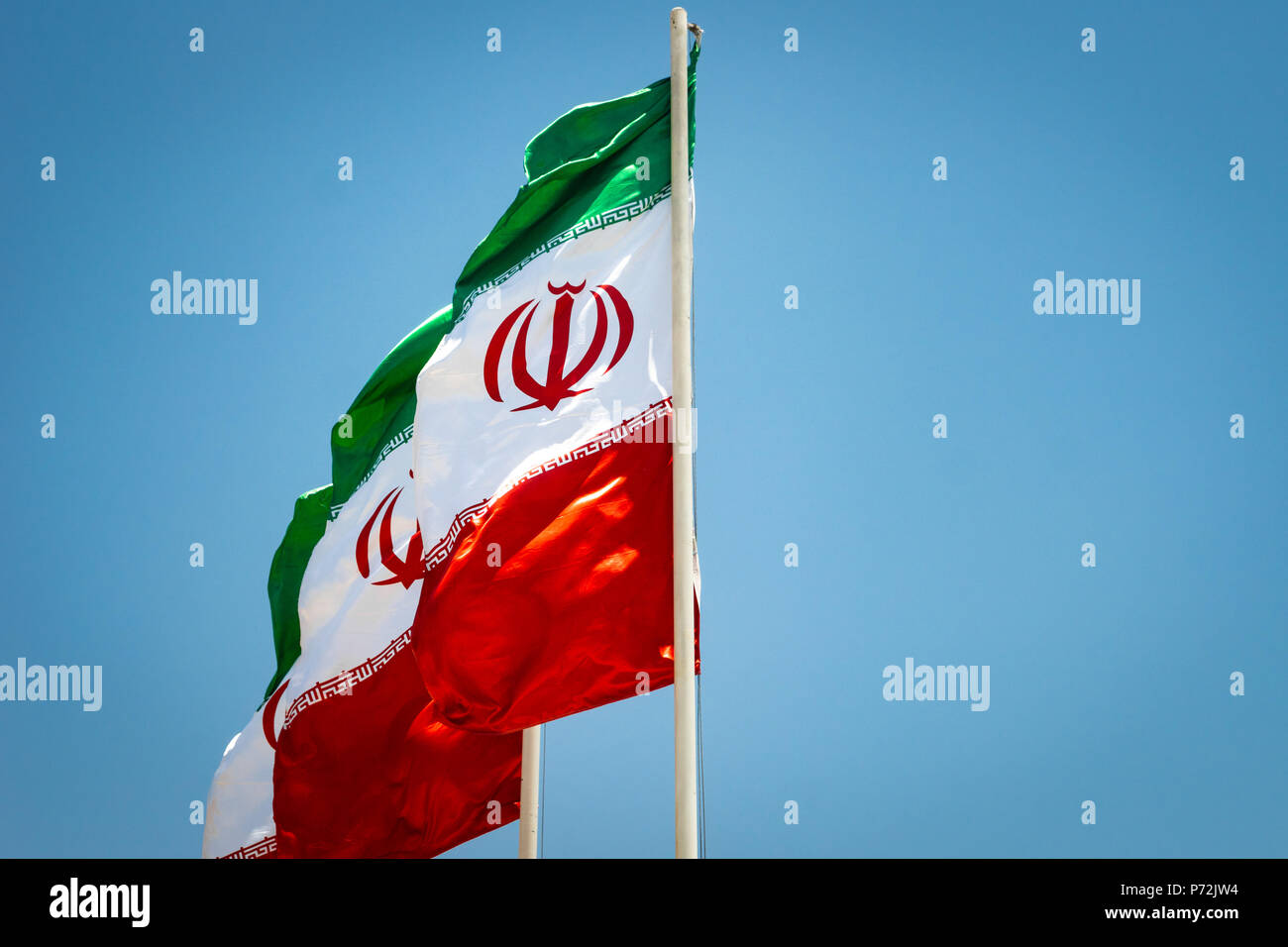 Iranian flags, flags of Islamic Republic of Iran, waving against blue sky Stock Photo