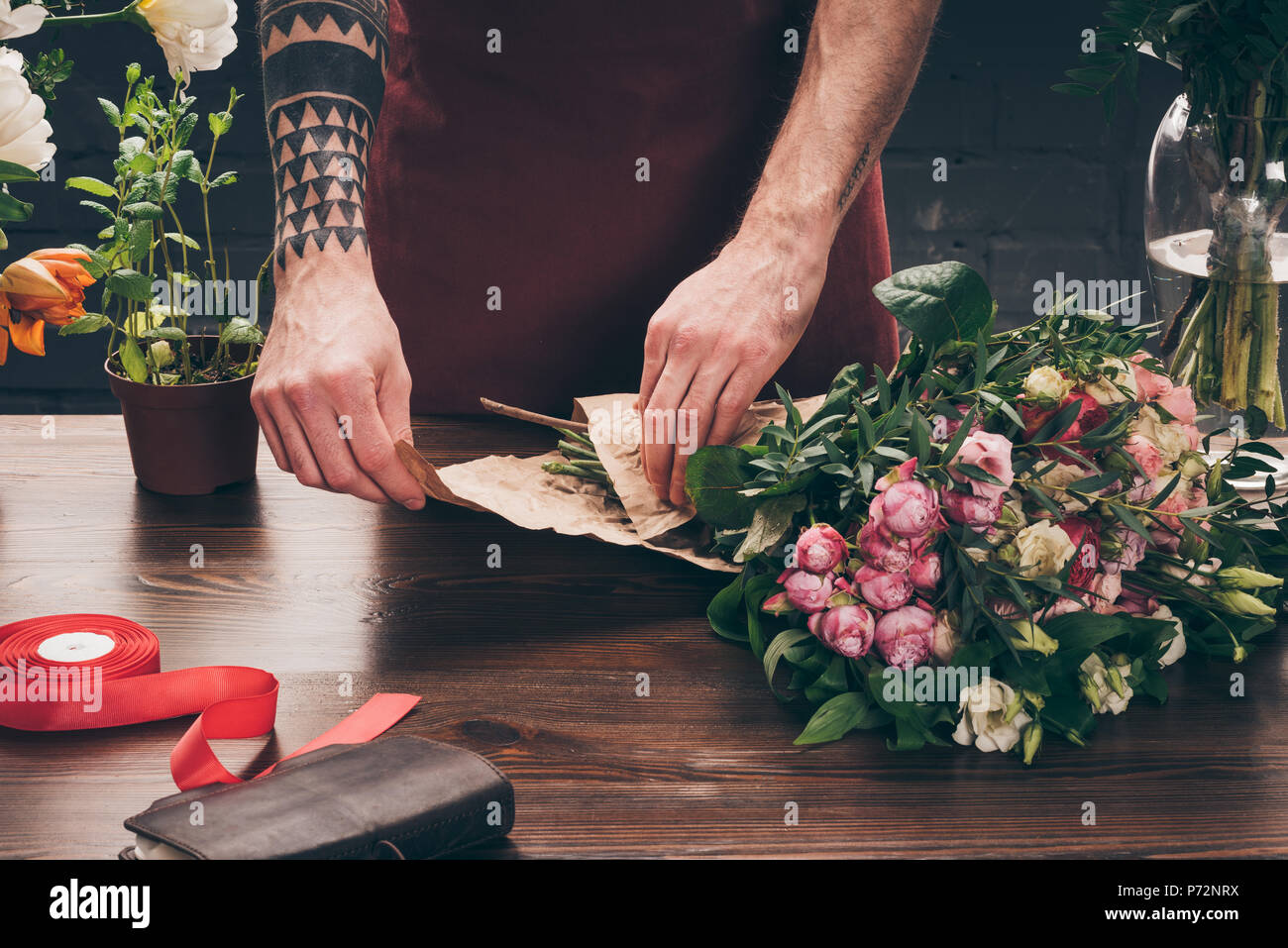 Cropped Image Of Male Florist With Tattoo On Hand Wrapping Bouquet