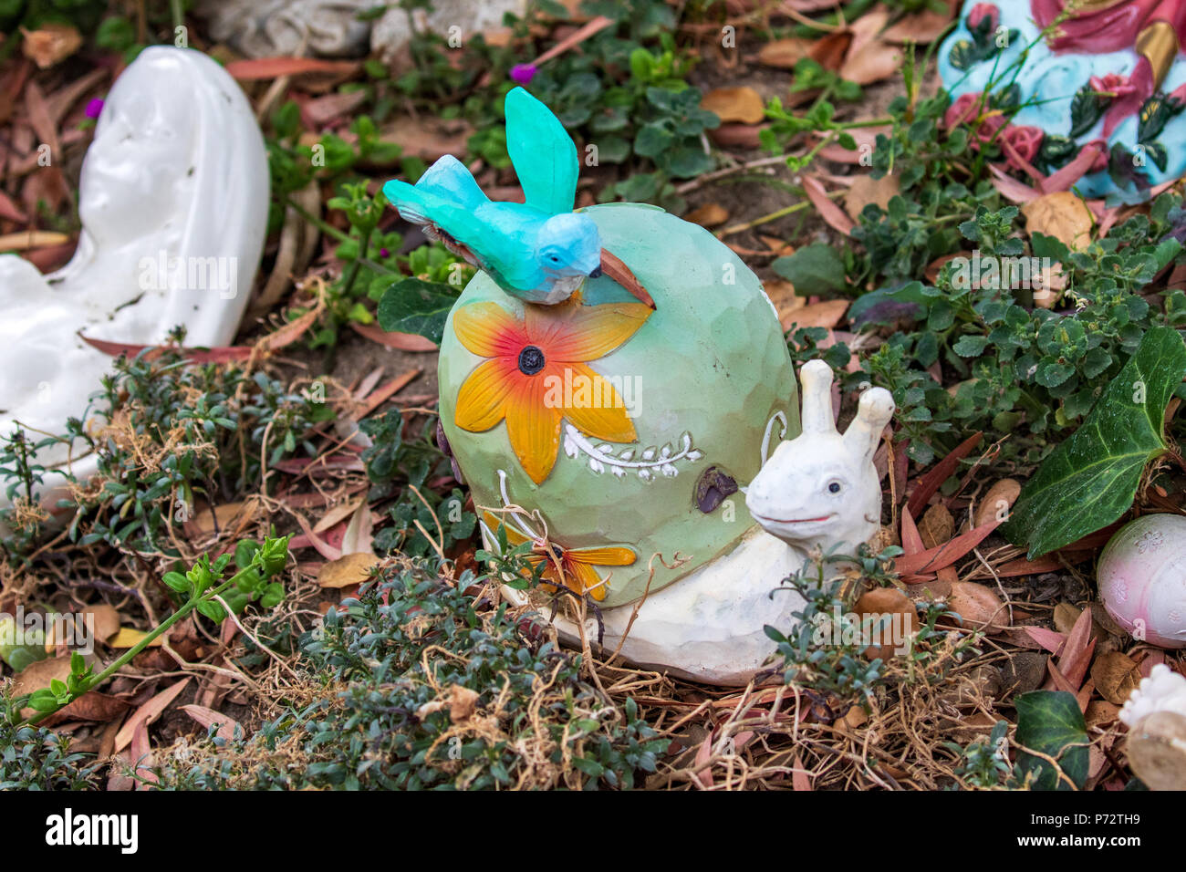 Whimsical Garden Art Decoration - Bluebird of Happiness perched on a snail's shell. The shell has a flower on it. Stock Photo