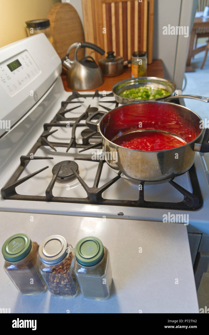 Cooking a pot of red tomato sauce and a pan of green peppers on a gas