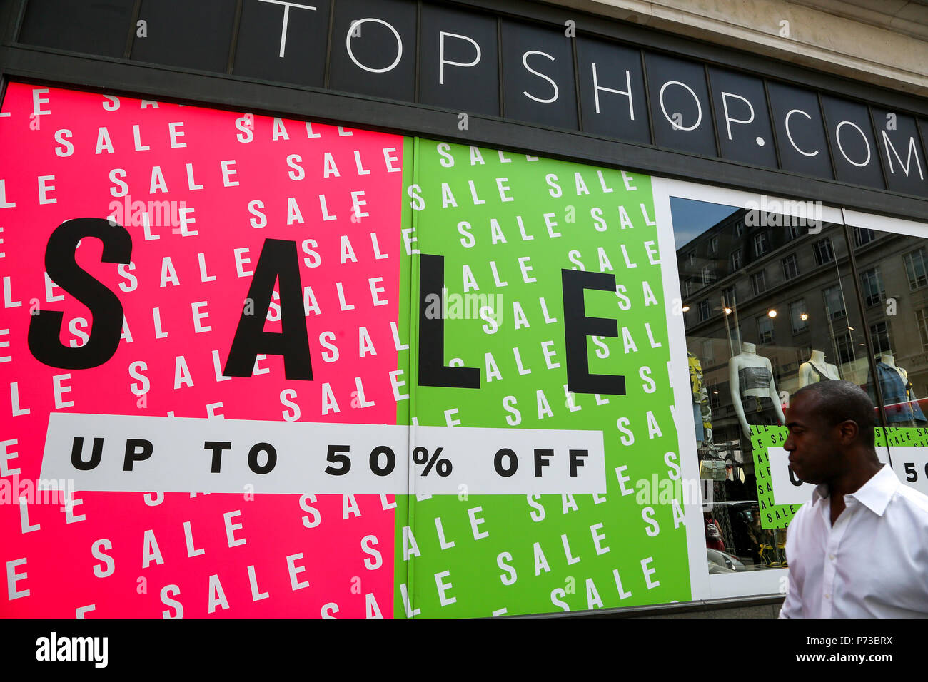 Oxford Street London. UK 4 July 2018 - Summer sales in Topshop store on  Oxford Street with up to 50% off. Shoppers walk past the summer sale window  display in stores on