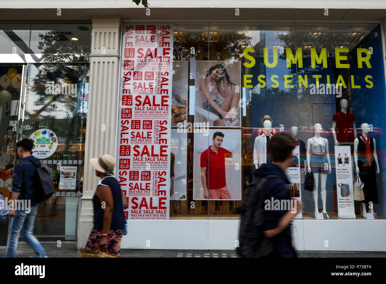 Regents Street London. UK 4 July 2018 - Summer sales in UNIQLO store on  Regents Street. Shoppers walk past the summer sale window display in stores  on Regents Street in London's west