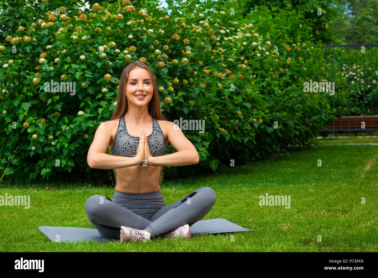 Peaceful young positive pregnant woman in gymnastic suit does yoga and  meditate sitting on mat on green grass on sunny warm summer day. Concept of  preparation for childbirth and positive attitude 16791340