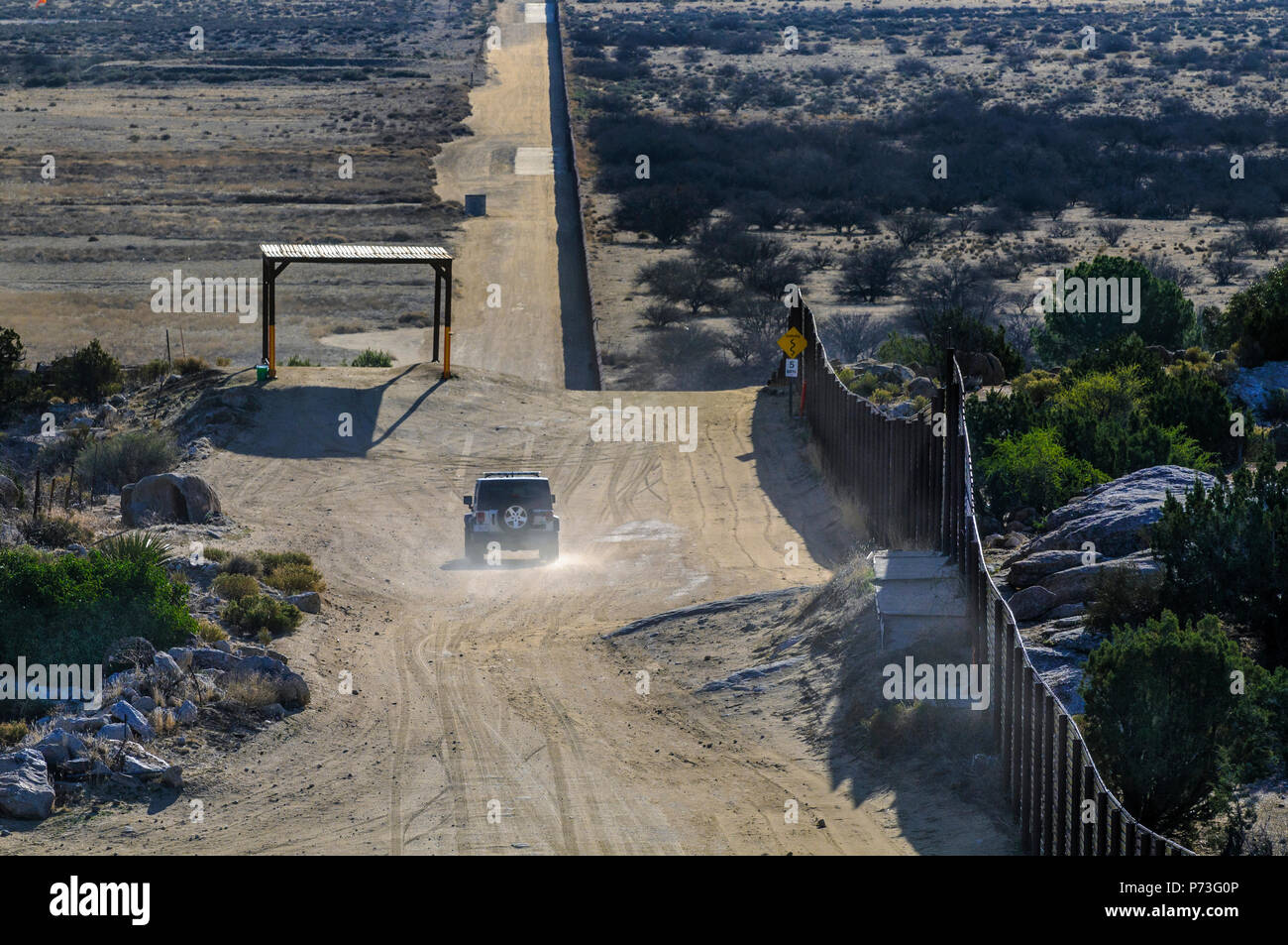 US Border Patrol vehicle beside steel 'landing mat' fence near Jacumba California, looking east, note shade structure on left built for CBP vehicle. Stock Photo