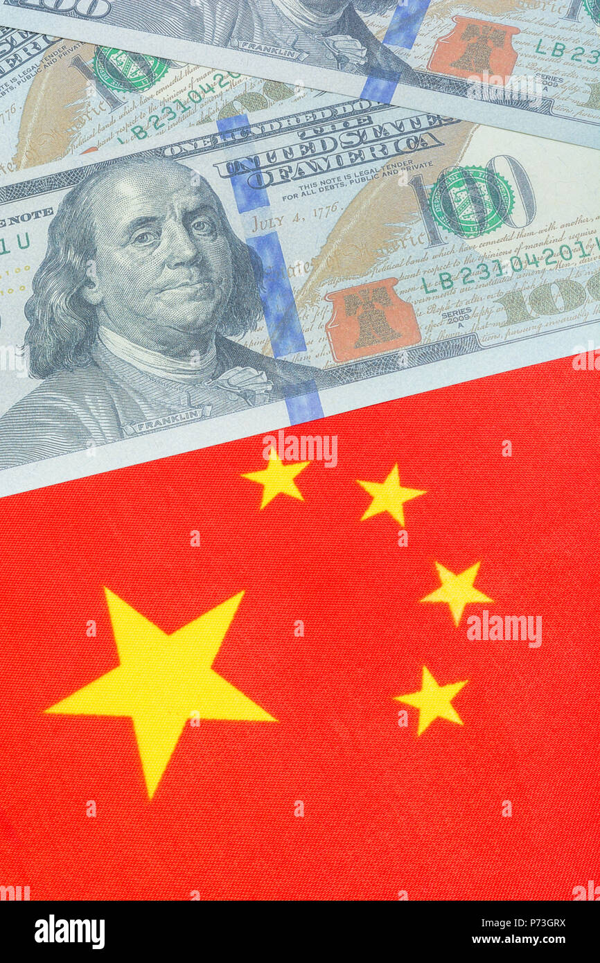 Chinese flag + US Dollar bills / Banknotes. For US-China trade war, Chinese tariffs on US soybeans. Lifelike $100 training bill, US China dispute. Stock Photo