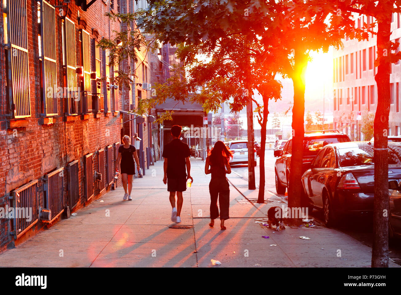 People walking down a street as the sun sets in Williamsburg, Brooklyn, New York, NY Stock Photo