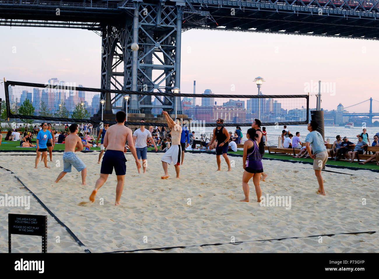 Asian people playing beach volleyball at Domino Park in Williamsburg