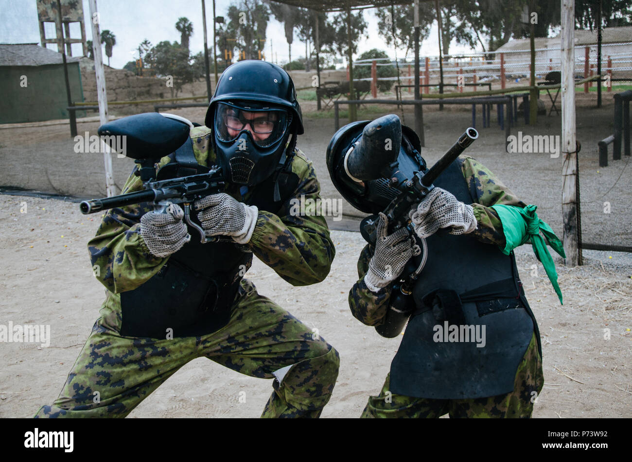 Paintball players in full gear at the shooting range, game weapons Stock Photo