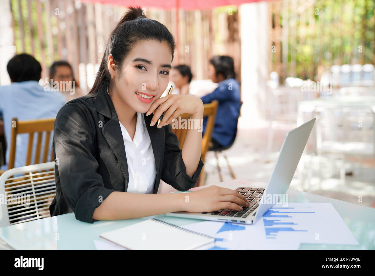 Portrait of smiling pretty young business woman in glasses sitting on ...