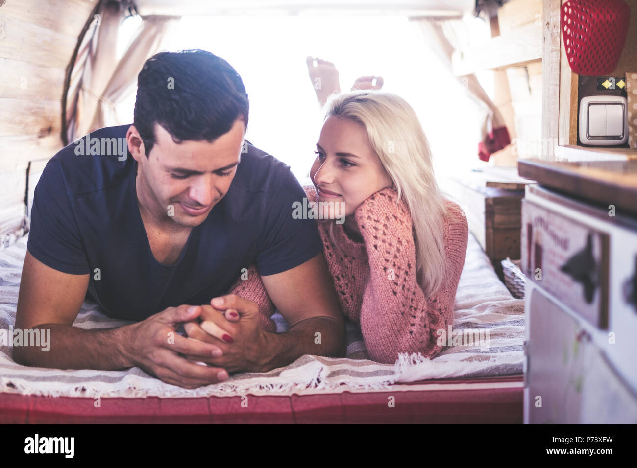 caucasian couple in love and romantic scene inside an old vintage camper ready to travel and have a vacation together with happiness and joy. blonde b Stock Photo
