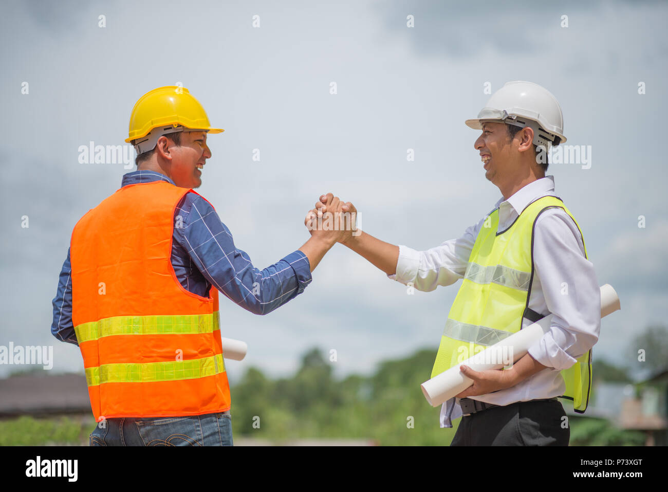 Handsome construction workers in protective helmets and vests are