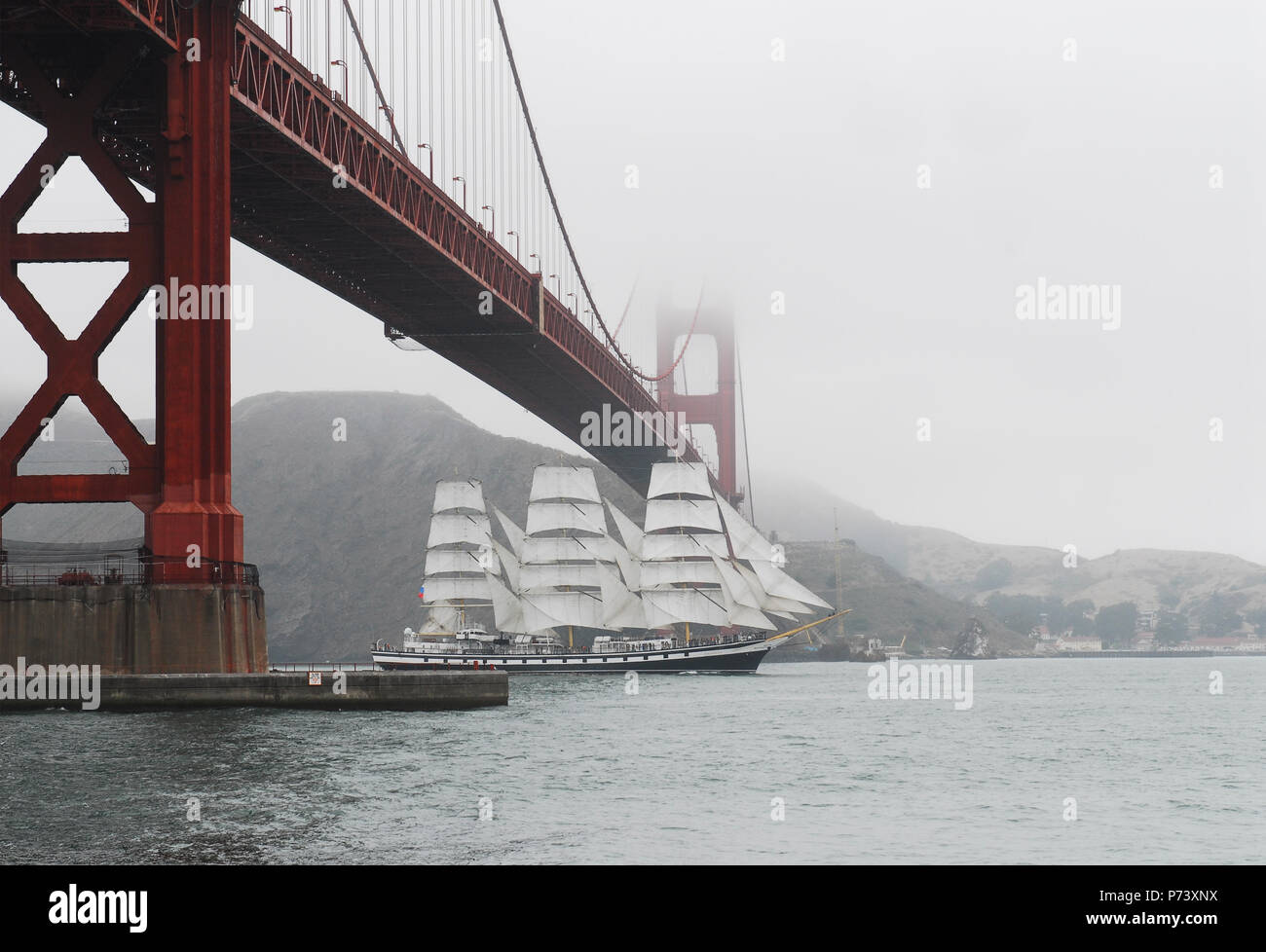 Russian tall ship Pallada sails under Golden Gate Bridge in the fog into San Francisco Bay Stock Photo