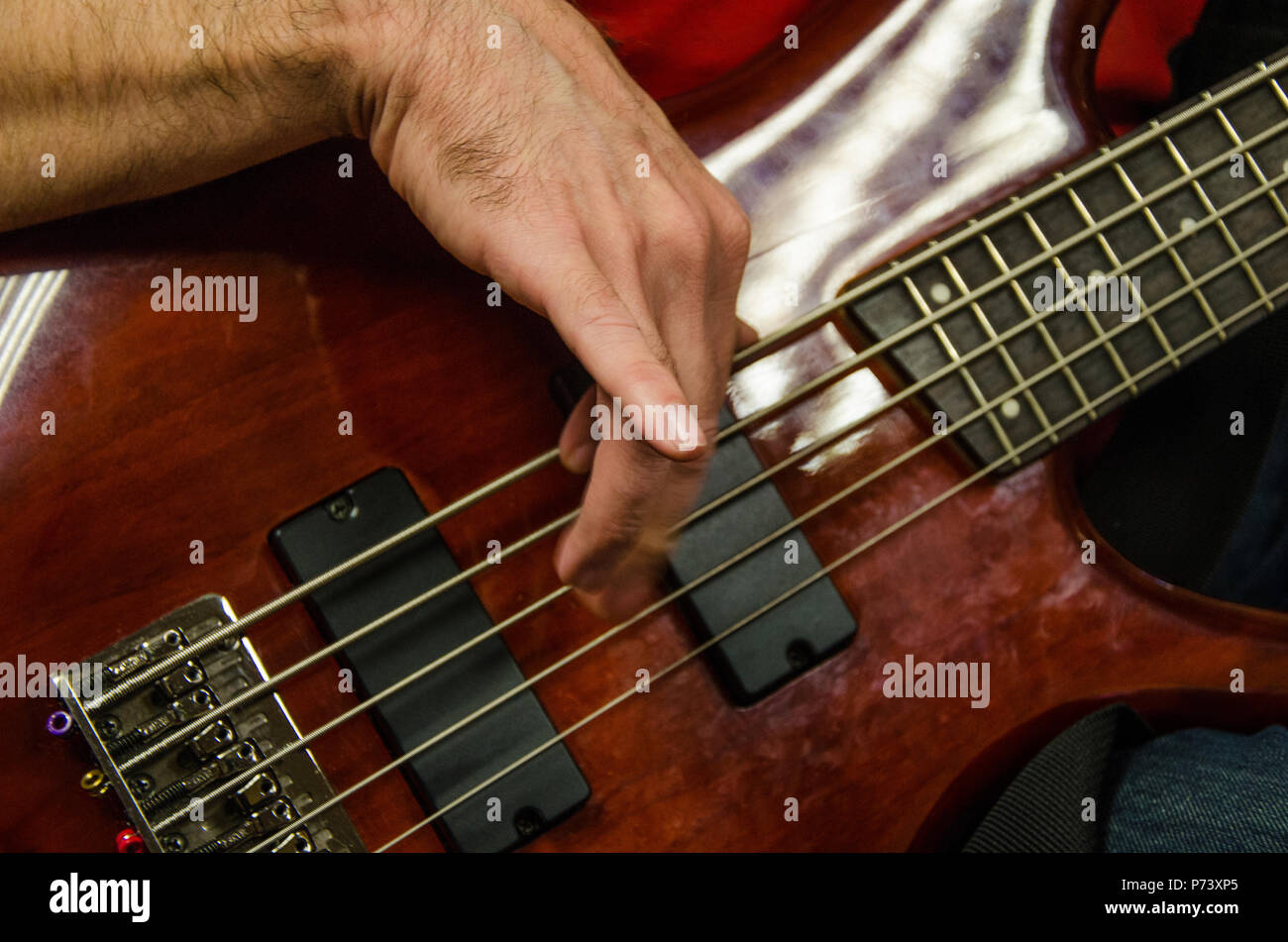 Closeup of photo of electric bass guitar player playing with hands Stock Photo