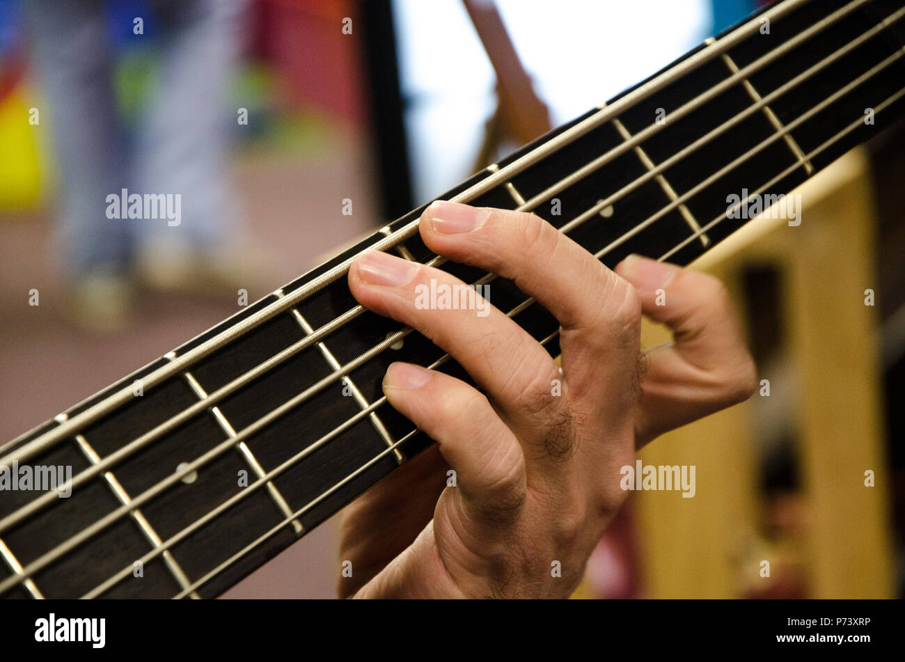 Closeup of photo of electric bass guitar player playing with hands