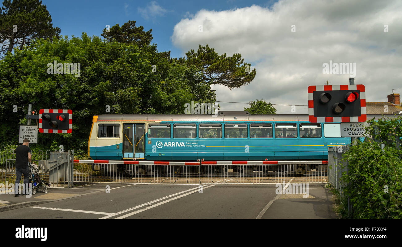 Diesel commuter train passing a level crossing as it arrives at Rhoose Cardiff International Airport railway station in the Vale of Glamorgan, Wales Stock Photo