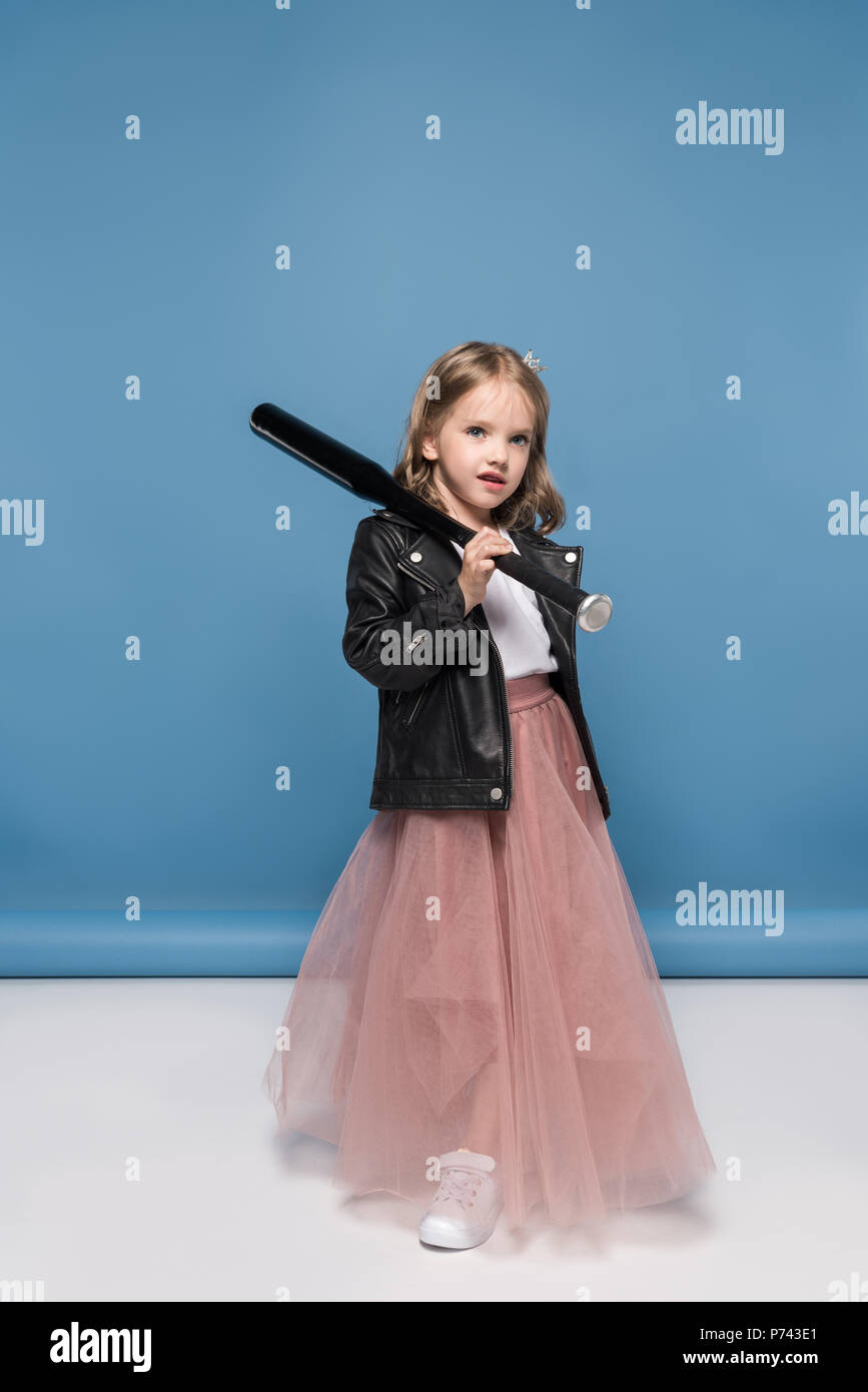 Cute little girl in leather jacket and pink skirt holding baseball bat and looking at camera Stock Photo