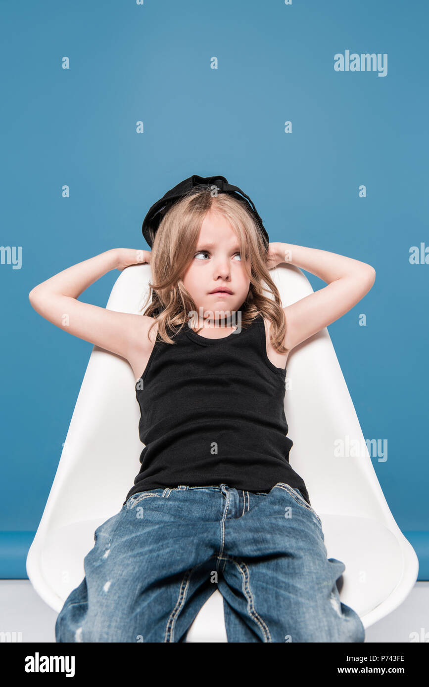 stylish kid girl looking away while sitting on chair Stock Photo - Alamy