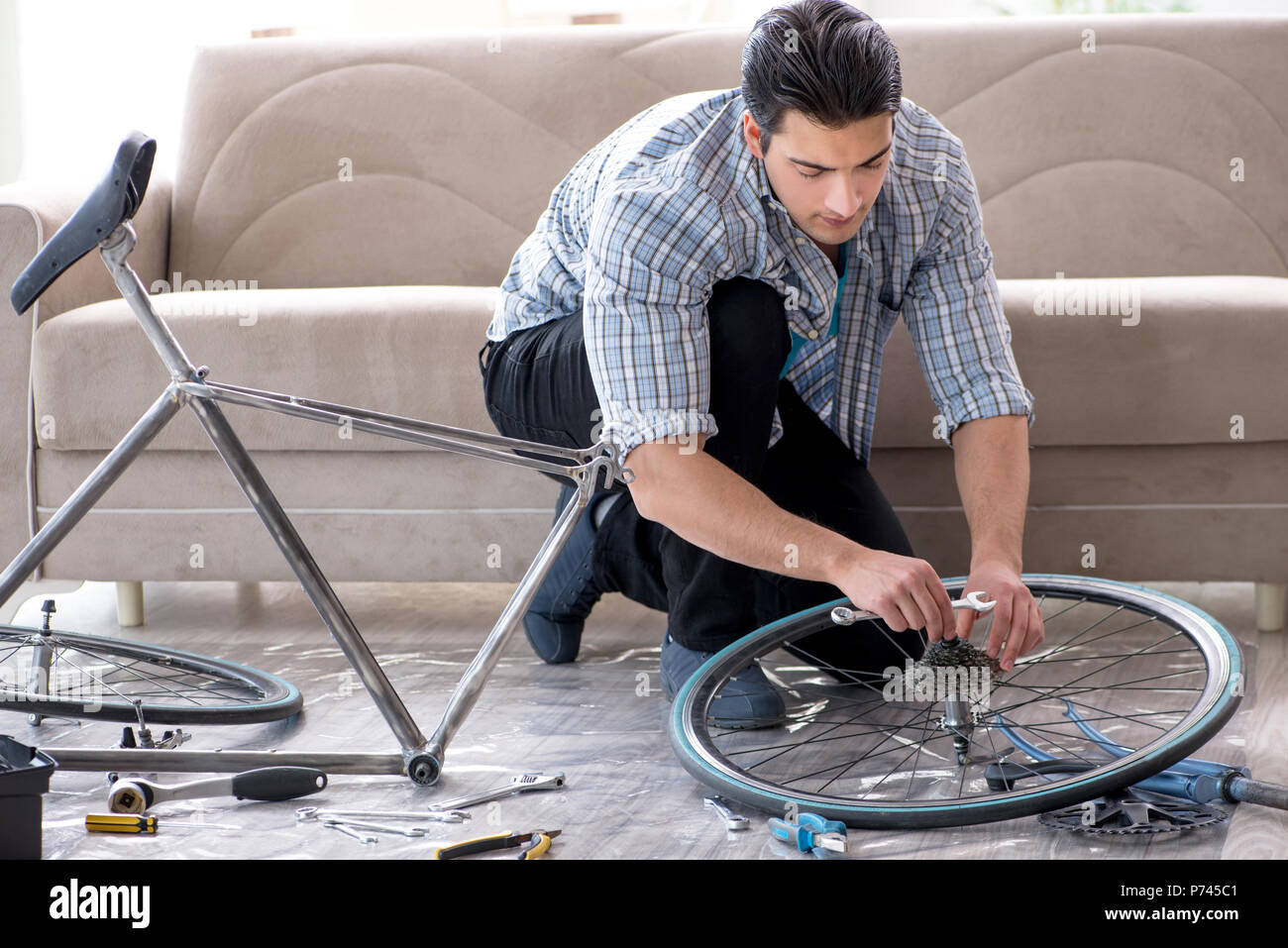 Young man repairing bicycle at home Stock Photo - Alamy