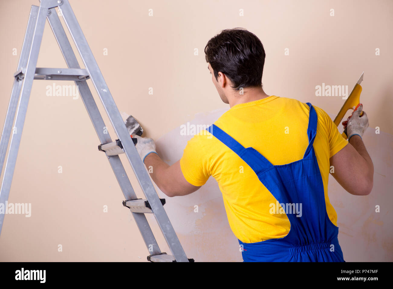 Young contractor employee applying plaster on wall Stock Photo