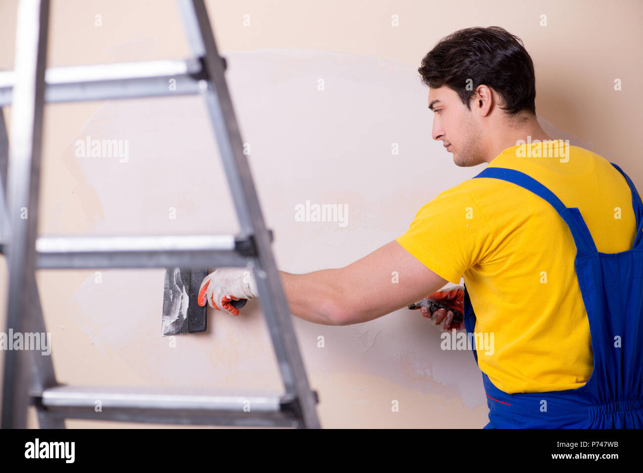 Young contractor employee applying plaster on wall Stock Photo