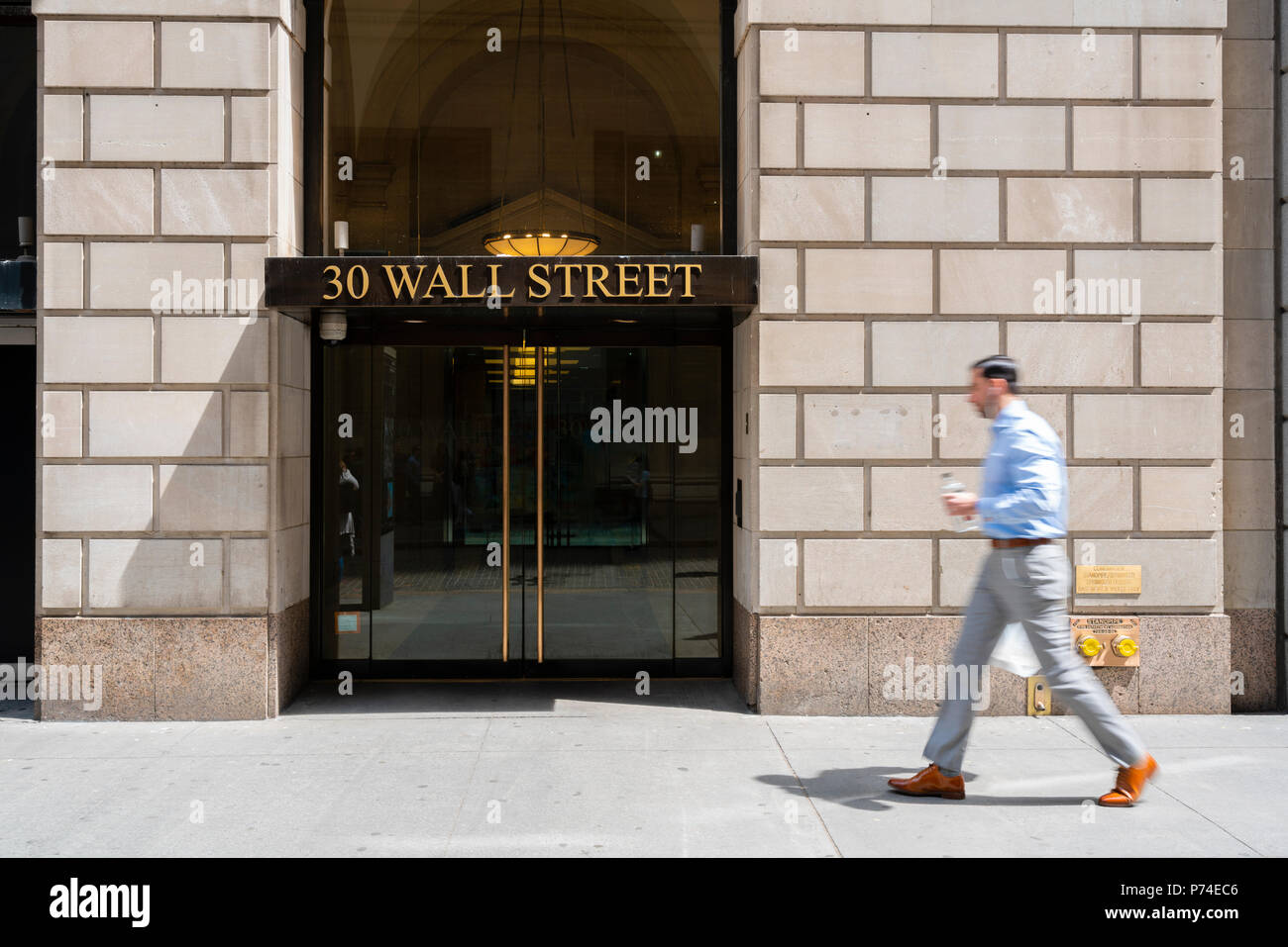 White collar worker walking pass a building at Wall Street Stock Photo