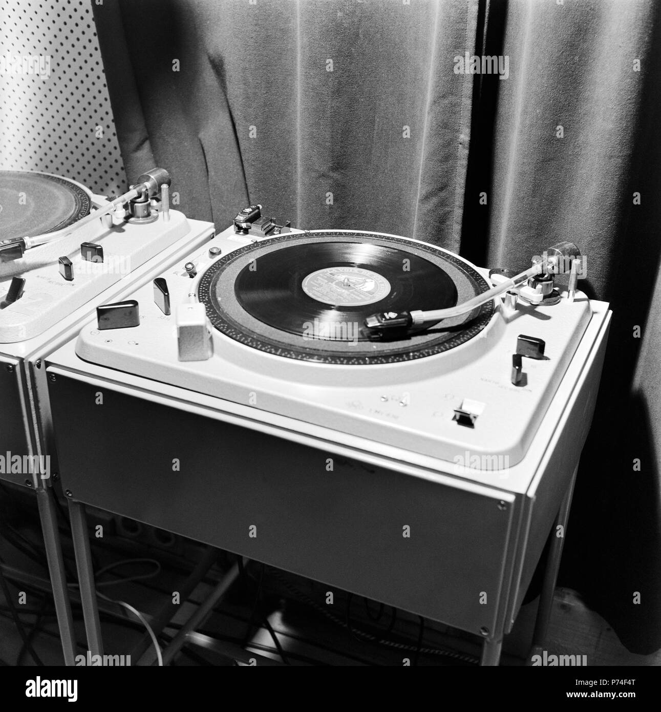Record player in the televison studio control room, 1958.  Yleisradion televisiotoiminnan alkuvaiheet. Pasilan alastudion äänitarkkaamossa on  kaksi levysoitinta. Lp-levy pyörii levysoittimessa. Äänilevyä soitetaan. Stock Photo