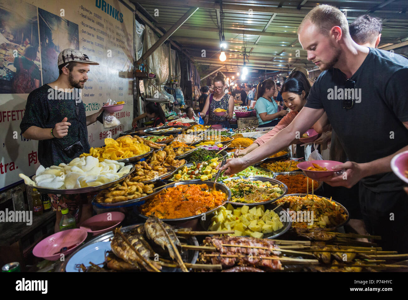 LUANG PRABANG, LAOS - 28 JUNE 2018 - People enjoy selecting food from the vegetarian buffet selection in Luang Prabang night market on June 28, 2018 i Stock Photo