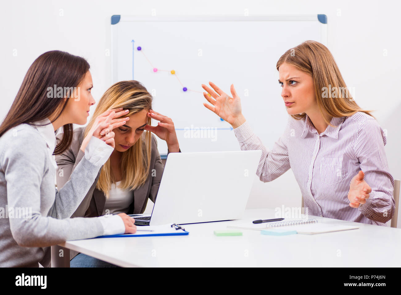 Three businesswomen are arguing at meeting in their office. Stock Photo