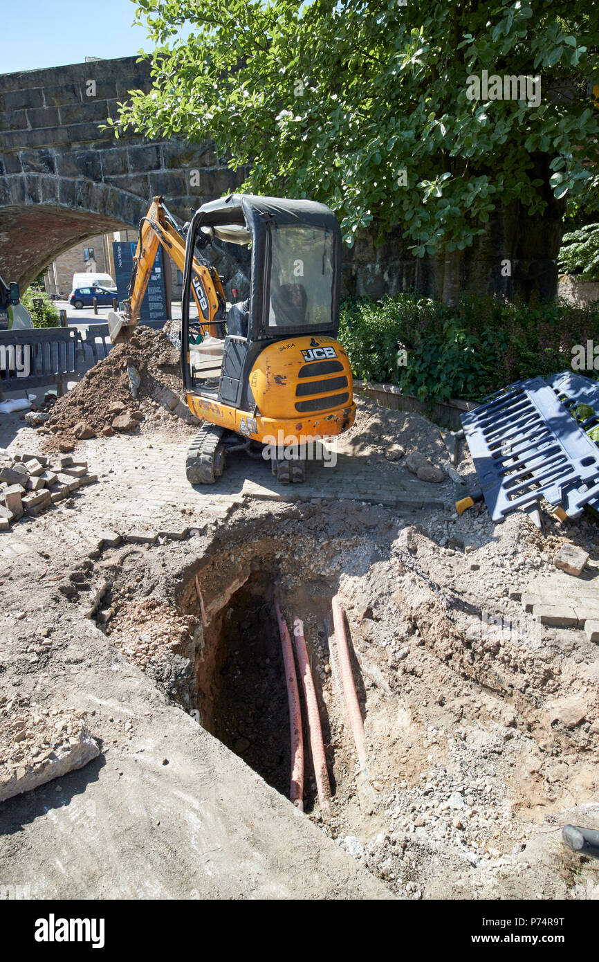 mini digger digging hole to access services underground in lancaster england uk Stock Photo