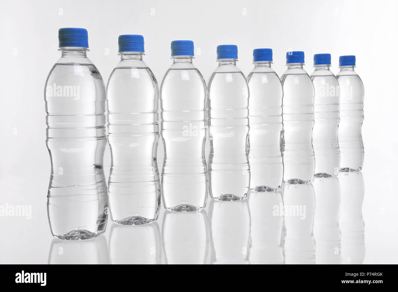 Eight plastic water bottles with blue lids in a row Stock Photo