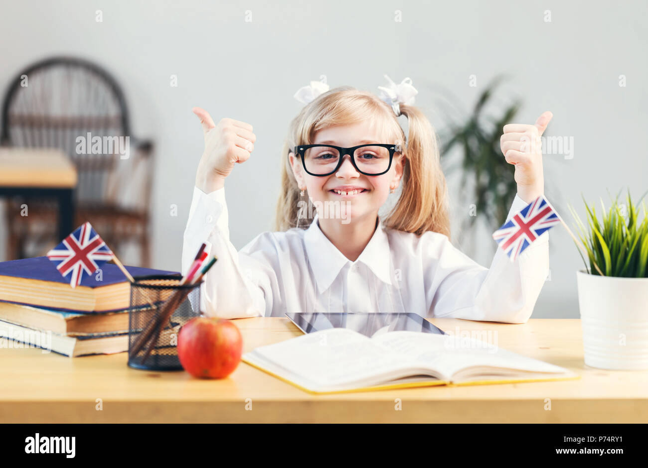 Happy smiling girl learning English language with book in light stylish classroom, studying success concept Stock Photo