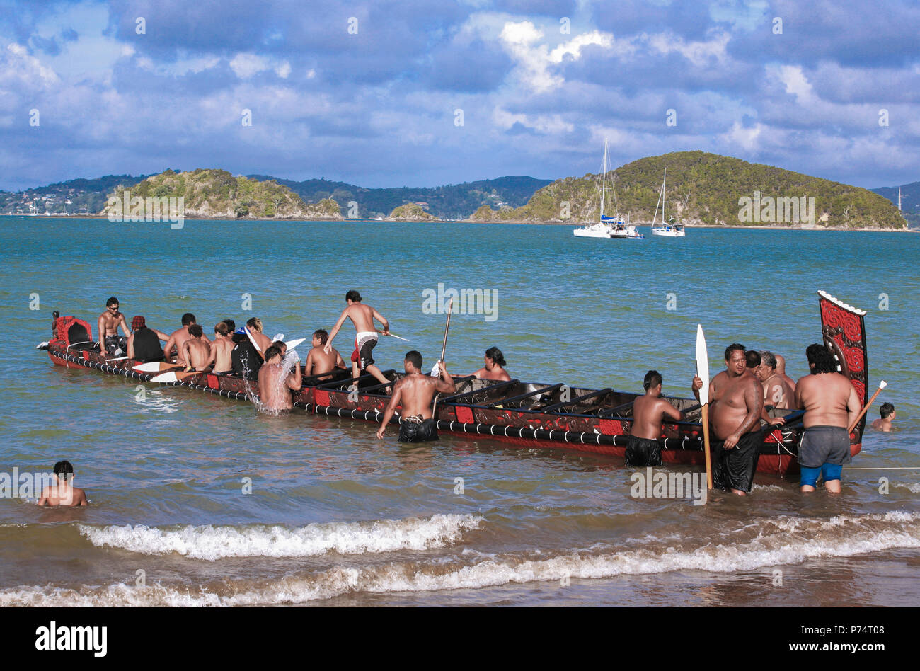 Maori Waka taua (war canoe) launching off beach at Waitangi during Waitangi Day celebrations, Bay of Islands, New Zealand Stock Photo