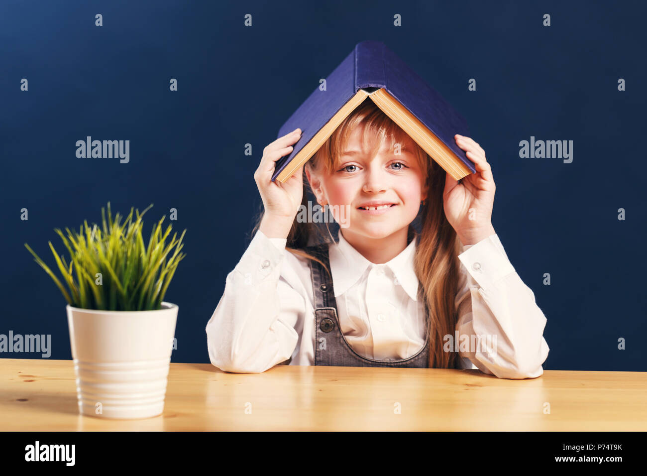 Portrait of successful kid girl student holding book over head before ...