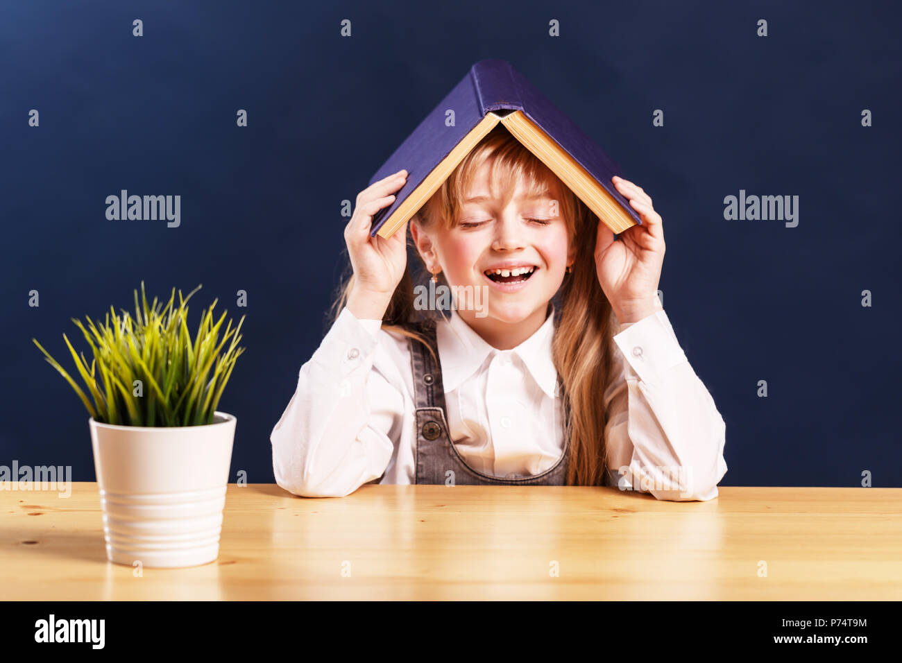 Portrait of successful smiling kid girl student holding book over head ...