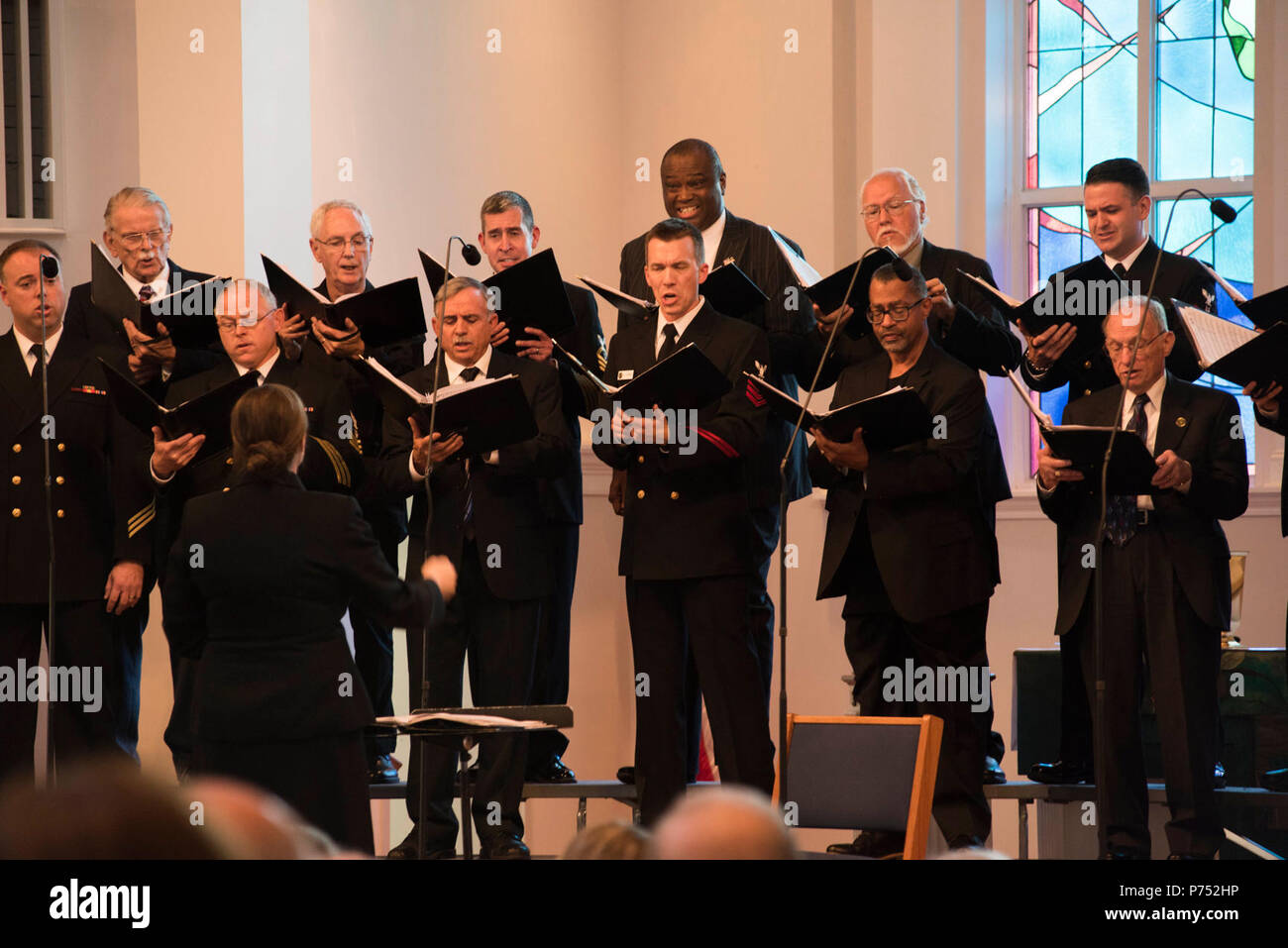 ANNANDALE, VIRGINIA  (October 30, 2016) Chief Petty Officer Casey Campbell, left, leads the men of the U.S. Navy Band Sea Chanters chorus during their 60th anniversary concert as they perform traditional sea chanteys. The Sea Chanters celebrated their 60th anniversary iin Annandale, Virginia, with a concert featuring alumni from the group. The chorus was formed as an all-male group in 1956 and tasked with perpetuating the songs of the sea. In 1980, the group added women to their ranks and expanded their repertoire to include everything from Brahms to Broadway. Stock Photo