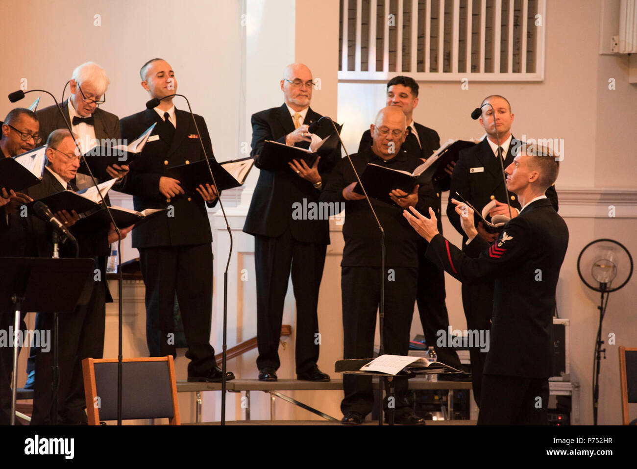 ANNANDALE, VIRGINIA  (October 30, 2016) Petty Officer 1st Class Adam Whitman, right, leads the men of the U.S. Navy Band Sea Chanters chorus during their 60th anniversary concert as they perform traditional sea chanteys. The Sea Chanters celebrated their 60th anniversary iin Annandale, Virginia, with a concert featuring alumni from the group. The chorus was formed as an all-male group in 1956 and tasked with perpetuating the songs of the sea. In 1980, the group added women to their ranks and expanded their repertoire to include everything from Brahms to Broadway. Stock Photo