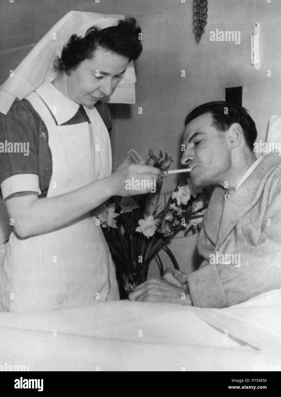 File photo dated 01/02/53 of National Health Service (NHS) nurse Nancy Lennox, lighting a cigarette for James Blair, who was rescued from the sinking of British Transport Commission's MV Princess Victoria during a storm, as he recovers in bed at Bangor Hospital, Northern Ireland. Stock Photo