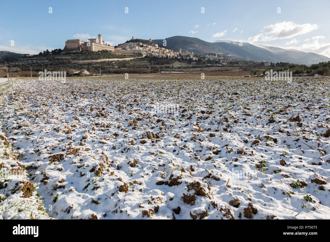 View of Assisi town (Umbria) in winter, with a country road covered by ...