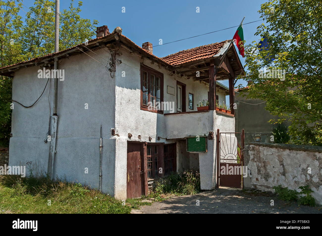 Part of street in the Paunovo village with old house, tree and fence, Sredna Gora mountain, Ihtiman, Bulgaria, Europe Stock Photo