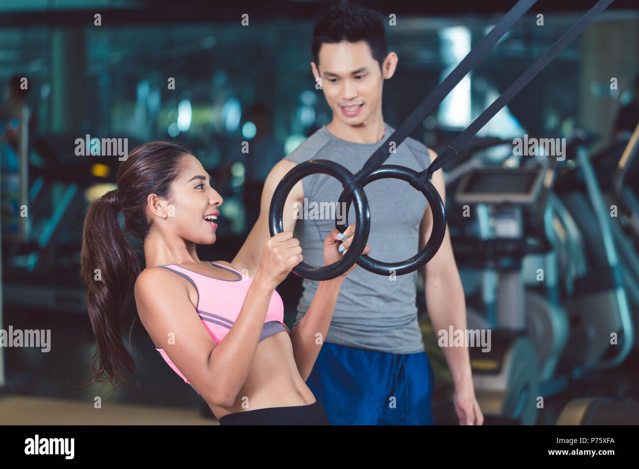 Fit woman doing ring biceps curl exercise during functional training