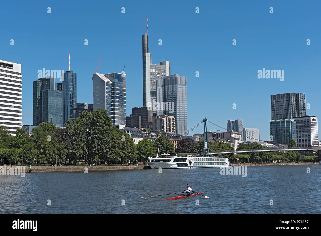 Rower in red boat on the main river in front of the skyline, frankfurt, germany Stock Photo