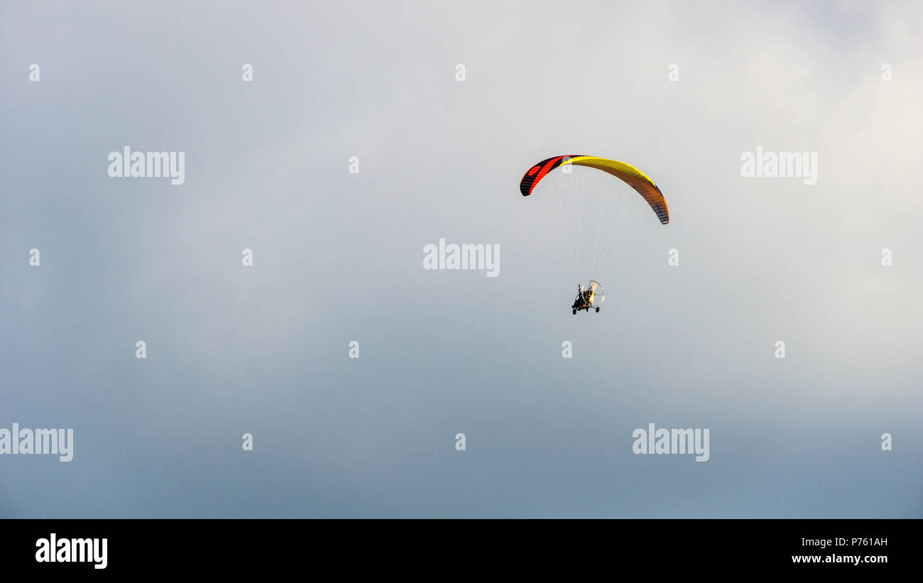 Sportsman flying with motorglider through dark clouds enjoying adrenaline Stock Photo