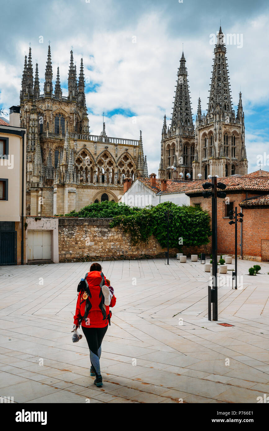 Lone female pilgrim on the Camino de Santiago Way of St. James at the historic centre of Burgos, Spain. Burgos Cathedral in background Stock Photo