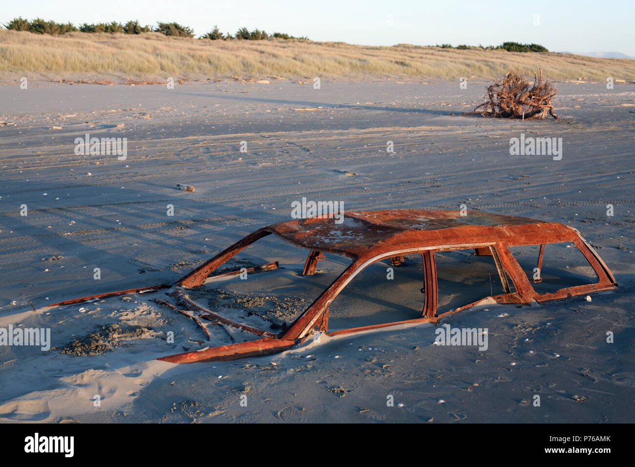 Rusted car wreck buried in sand on beach Stock Photo
