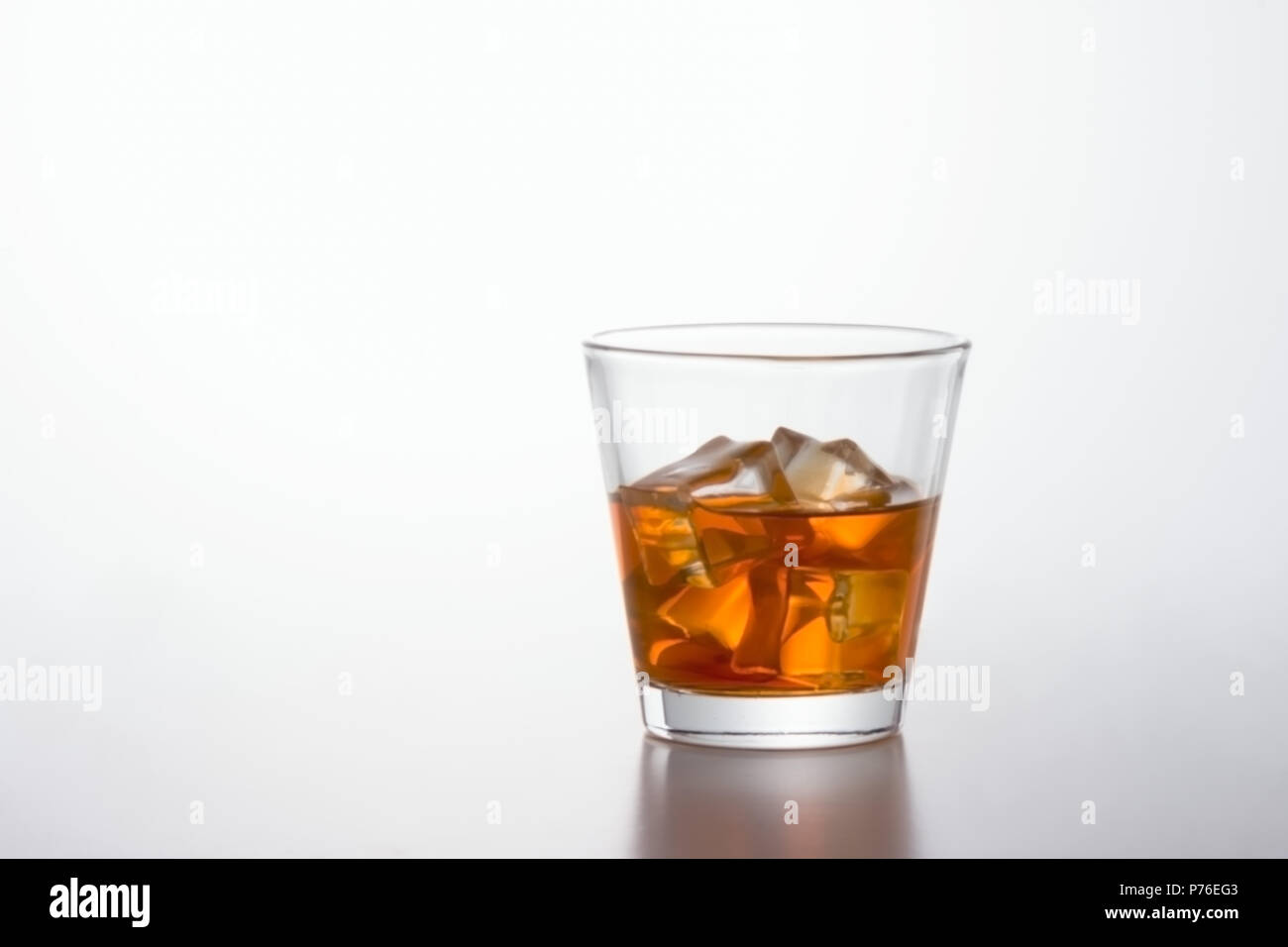 Glass of brandy and ice cubes on white background Stock Photo